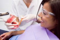 Стоматолог, що показує модельні зуби пацієнтці в стоматологічній клініці — стокове фото