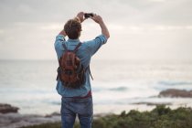 Вид сзади на человека, фотографирующего с помощью мобильного телефона — стоковое фото