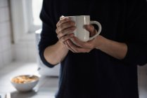 Середина человека, держащего чашку черного кофе дома — стоковое фото