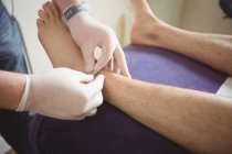 Крупный план физиотерапевта, выполняющего сухую иглу на ноге пациента в клинике — стоковое фото