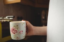 Средняя секция женщины, держащей чашку кофе на кухне дома — стоковое фото