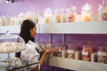 Хозяйка магазина смотрит на банку турецких сладостей на полке в магазине — стоковое фото