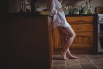 Женщина, использующая мобильный телефон на кухне дома — стоковое фото