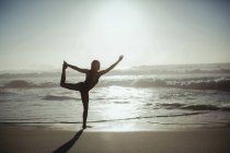 Mujer realizando yoga en la playa al atardecer - foto de stock