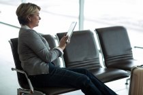 Бізнес-леді, використовуючи цифровий планшет в зоні очікування в терміналі аеропорту — стокове фото