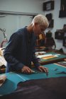 Artisanat attentif travaillant sur un morceau de cuir en atelier — Photo de stock