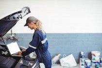 Female mechanic using laptop in repair garage — Stock Photo