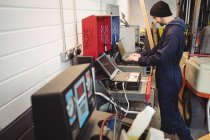 Mecánico usando el ordenador portátil en el garaje de reparación - foto de stock