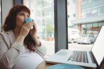 Schwangere Geschäftsfrau trinkt Kaffee in Büro-Cafeteria — Stockfoto