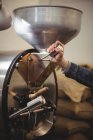 Hand of man using coffee grinding machine in coffee shop — Stock Photo