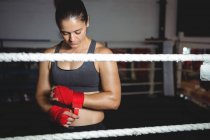 Boxer féminin portant une sangle rouge au poignet dans un studio de fitness — Photo de stock