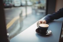 Рука руководителя держит кофе у стойки в кафетерии — стоковое фото