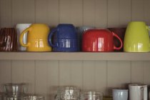 Nahaufnahme bunter Tassen im Küchenregal — Stockfoto