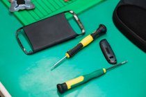Close-up of mobile phone case with screwdriver in repair centre — Stock Photo
