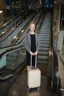 Businesswoman standing near escalator with luggage at airport — Stock Photo