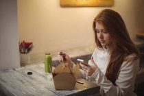 Рыжая женщина использует мобильный телефон во время еды салата — стоковое фото
