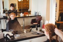 Female hairdresser styling clients hair in saloon — Stock Photo