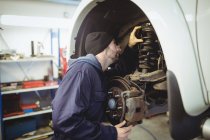 Meccanico esaminando un freno a disco ruota auto in garage di riparazione — Foto stock