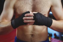 Средняя секция боксера, носящего черный ремень на запястьях в фитнес-студии — стоковое фото