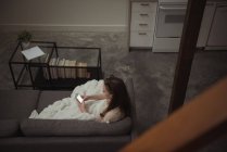 Высокий угол обзора женщины, пользующейся мобильным телефоном на диване дома — стоковое фото