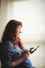 Embarazada mujer de negocios usando el teléfono móvil mientras toma café en la oficina - foto de stock