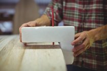 Nahaufnahme eines Mannes mit Markierungsmesser auf Surfbrett in Werkstatt — Stockfoto