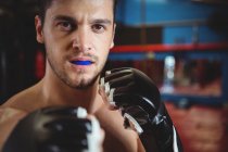 Boxer com gumshield realizando postura de boxe no estúdio de fitness — Fotografia de Stock