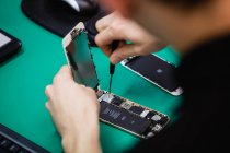 Nahaufnahme eines Mannes, der sein Handy in einem Reparaturzentrum repariert — Stockfoto