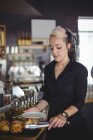 Waitress serving muffin in a plate at counter in cafe — Stock Photo