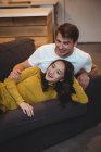 Весела пара разом лежачи на дивані у вітальні на дому — стокове фото