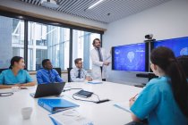 Doctor giving presentation to team of interim doctors at conference room — Stock Photo
