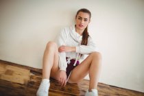 Молодая случайная женщина, сидящая на полу в танцевальной студии — стоковое фото