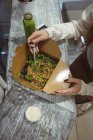 Vista de ángulo alto de la mujer comiendo ensalada en el interior - foto de stock