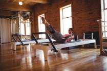 Woman practicing pilates on reformer in fitness studio — Stock Photo