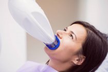 Paciente femenina que recibe tratamiento con luz dental en clínica dental - foto de stock