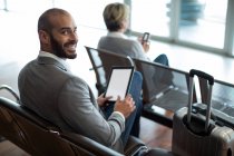 Ritratto di uomo d'affari sorridente che utilizza tablet digitale in sala d'attesa al terminal dell'aeroporto — Foto stock