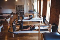 Mulheres praticando pilates em reformadores em estúdio de fitness — Fotografia de Stock