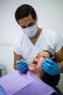 Стоматолог, осматривающий женские зубы пациента в клинике — стоковое фото