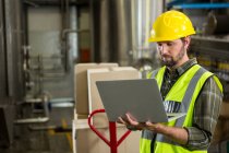 Serious male worker using laptop in distribution warehouse — Stock Photo