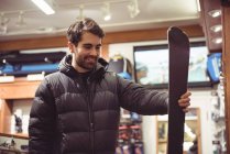 Bello uomo che sceglie lo sci in un negozio — Foto stock