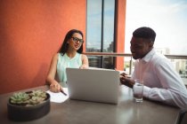 Бізнесмен і колега обговорюють ноутбук в офісі — стокове фото