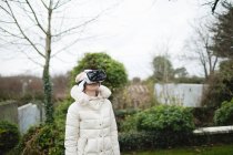 Жінка в лютому пальто, використовуючи гарнітуру віртуальної реальності на відкритому повітрі — стокове фото