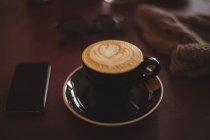 Taza de café con smartphone en mesa de madera - foto de stock