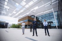 Groupe de gens d'affaires confiants debout les bras croisés devant un immeuble de bureaux — Photo de stock