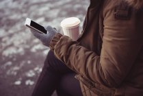 Frau benutzt im Winter Handy am Flussufer — Stockfoto