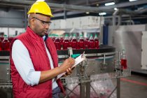 Serious male employee noting about products in juice factory — Stock Photo