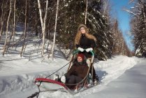 Pareja montando el trineo en una tierra nevada - foto de stock