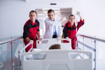 Medici che spingono letto barella di emergenza in corridoio in ospedale — Foto stock