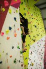 Donna che pratica arrampicata su parete artificiale in palestra — Foto stock