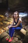 Nachdenkliche Frau sitzt auf Felsen im Wald — Stockfoto